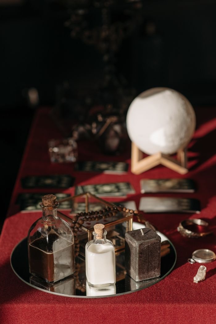 An enchanting fortune telling set with tarot cards, crystal ball, and mystical objects on a red cloth.